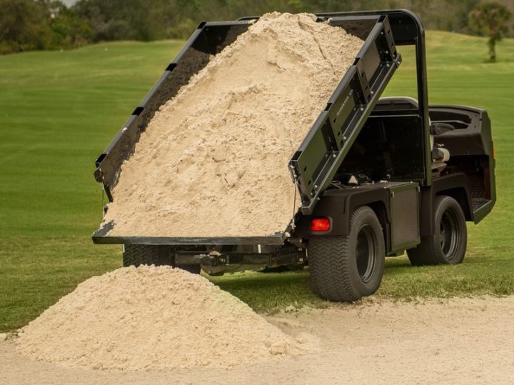 Cushman Truckster XD dumping sand into a bunker on a golf course