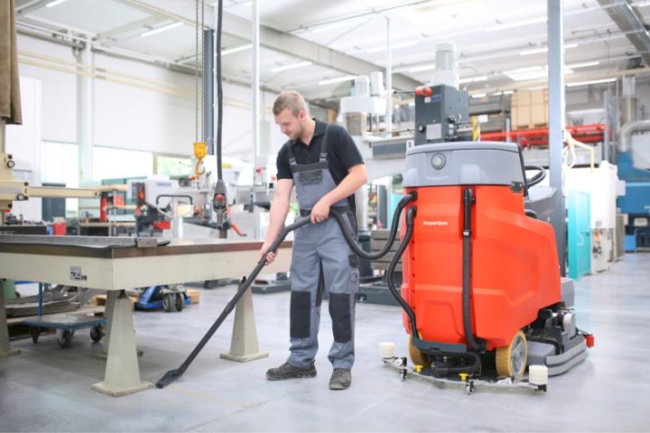 PowerBoss Scrubmaster B120 cleaning a factory floor with vacuum wand accessory