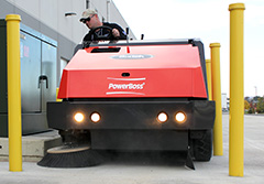 A rider floor sweeper cleaning a parking lot