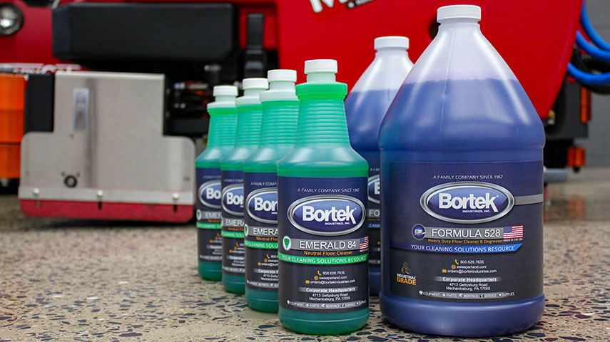 Cleaning chemical bottles lined up in front of a floor scrubber