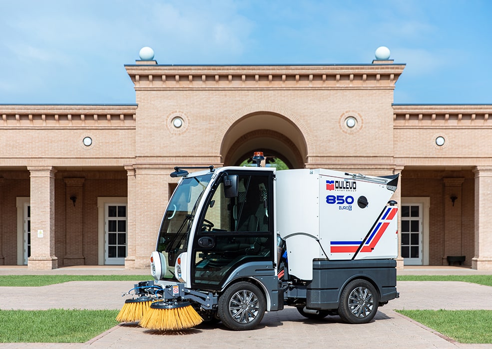 A Dulevo 850 Sweeper parked in front of a building.